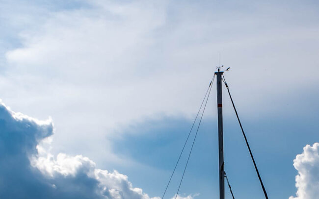 the mast of a ship against a cloudy sky
