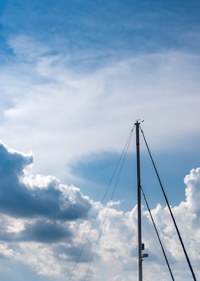 the mast of a ship against a cloudy sky