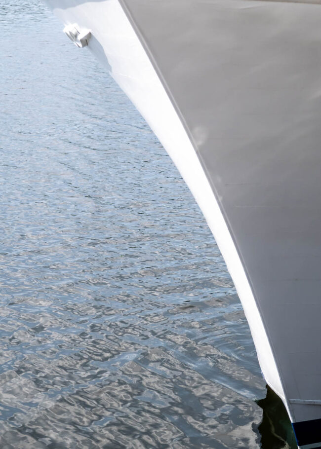 the bow of a white ship constrasted against the dark water