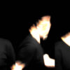 A composite of three vertical video stills against a black background. Each panel captures a high-contrast, ghostly profile of a figure in motion blur. The face is abstracted into streaks of blown-out white and warm light, creating a sense of rapid, loop-based repetition and fragmentation.